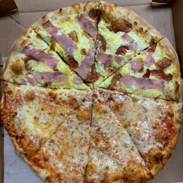 Half cheese and half bacon and ham pizza in a cardboard box from Espresso Pizza.