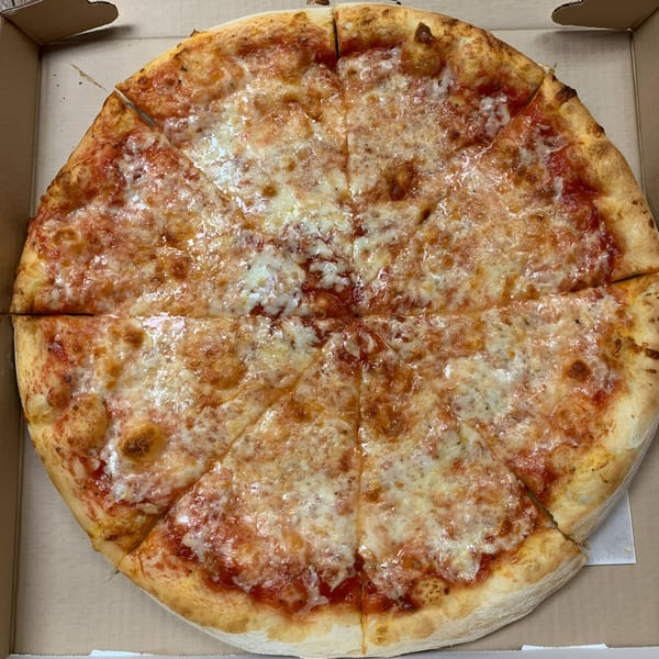 A whole Espresso Pizza cheese pizza, cut into eight slices, in a cardboard delivery box.