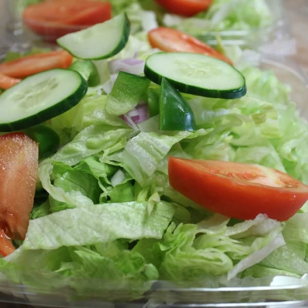 Fresh garden salad with crisp lettuce, sliced tomatoes, cucumbers, green peppers, and red onions.