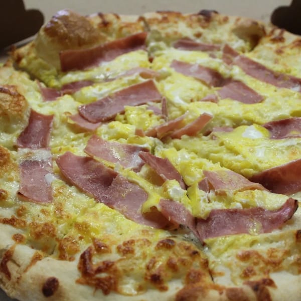 Espresso Pizza's breakfast pizza topped with scrambled eggs and ham slices.