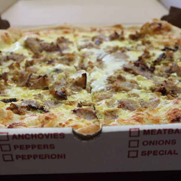 Espresso Pizza's white pizza with steak and cheese, sliced in a delivery box.