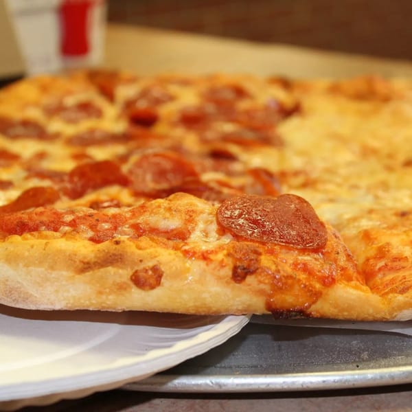 Close-up of a large, rectangular pepperoni pizza with a thick crust on a metal tray.